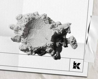 Een gestructureerd, onregelmatig gevormd wit fragment van een mineraal of materiaal, rustend op een lichte achtergrond, met een klein logo rechtsonder.