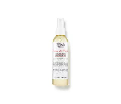 A spray bottle of Kiehl's Creme de Corps nourishing dry body oil, showcasing a sleek design with a white label and red text.