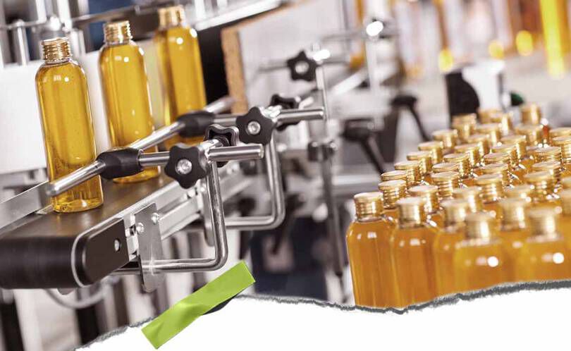 Een geautomatiseerde bottellijn met heldere flessen gevuld met gele vloeistof en metalen klemmen, die een drukke productieomgeving laat zien.