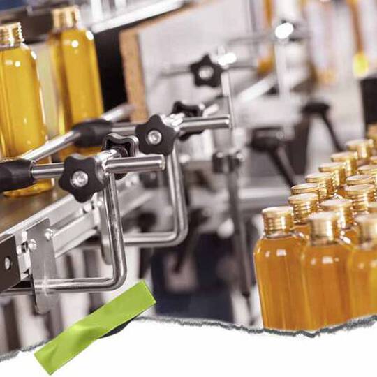 Een geautomatiseerde bottellijn met heldere flessen gevuld met gele vloeistof en metalen klemmen, die een drukke productieomgeving laat zien.