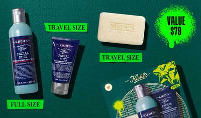 Een afbeelding, tegen een donkergroene getextureerde achtergrond, toont drie Kiehl’s producten. Een blauwe fles "KIEHL’S FACIAL FUEL INVIGORATING FACE WASH" is gemarkeerd met "FULL SIZE" in felgroen. Een donkerblauwe tube "KIEHL’S FACIAL FUEL MOISTURIZER" is gemarkeerd met "TRAVEL SIZE" in felgroen. Een stuk "KIEHL’S 'ULTIMATE MAN' BODY SCRUB SOAP" is ook gemarkeerd met "TRAVEL SIZE" in felgroen. Rechtsonder is een gedeeltelijk zichtbare groene Kiehl’s geschenkdoos te zien, met dezelfde drie producten.