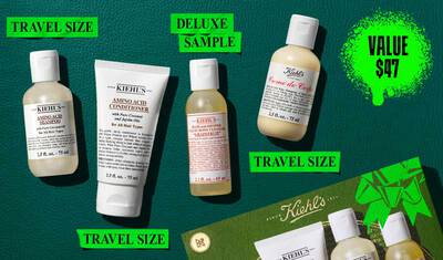 Een flat lay-afbeelding op een donkergroene achtergrond toont een Kiehl's productset, uitgelicht met een felgroene waardeprijsafbeelding. De set omvat vier reisformaat producten: links een 75 ml fles Kiehl's Amino Acid Shampoo; ernaast een 75 ml tube Kiehl's Amino Acid Conditioner; in het midden een 65 ml luxe proeffles Kiehl's Bath and Shower Liquid Body Cleanser in de geur 'Grapefruit'; en rechts een 75 ml fles Kiehl's Creme de Corps. Een groene Kiehl's geschenkdoos met een opvallende lintafbeelding is gedeeltelijk zichtbaar in de rechterbenedenhoek van de afbeelding.