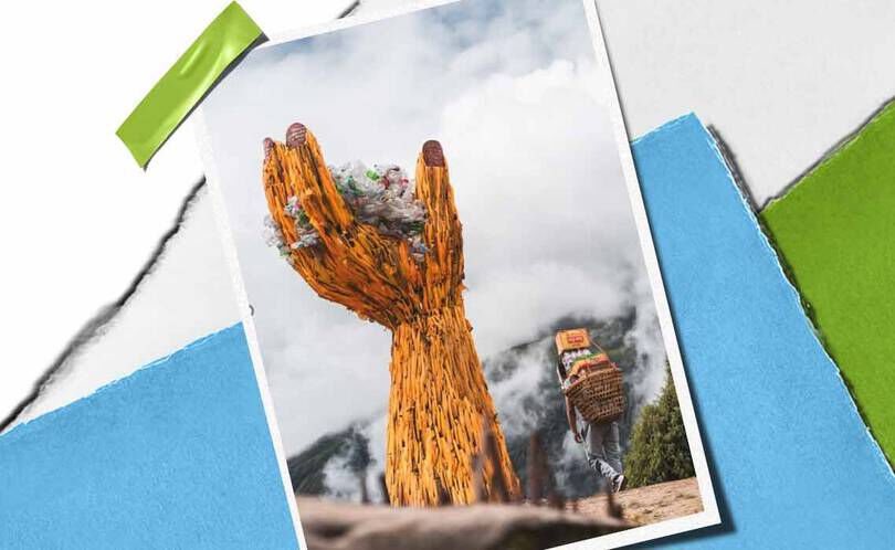 Een torenhoge, houten handsculptuur houdt een stapel afval vast, als symbool voor milieubewustzijn, met in de buurt een persoon die goederen draagt.