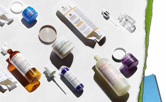 Een reeks huidverzorgingsproducten op een lichte achtergrond, waaronder flesjes, potjes en druppelaars in verschillende kleuren en vormen.