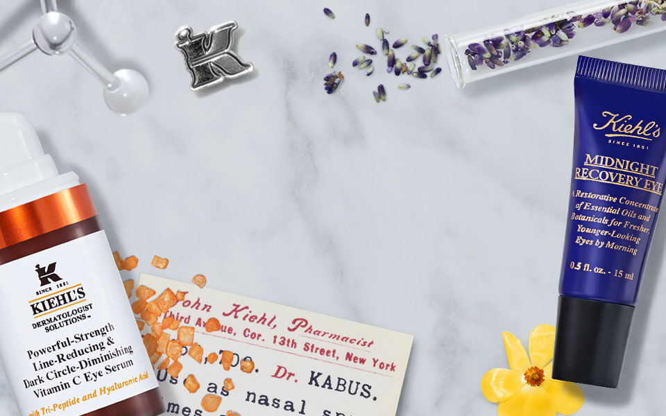 Een marmeren achtergrond met verschillende huidverzorgingsproducten, waaronder flessen en tubes, naast oranje zout en een bloem.