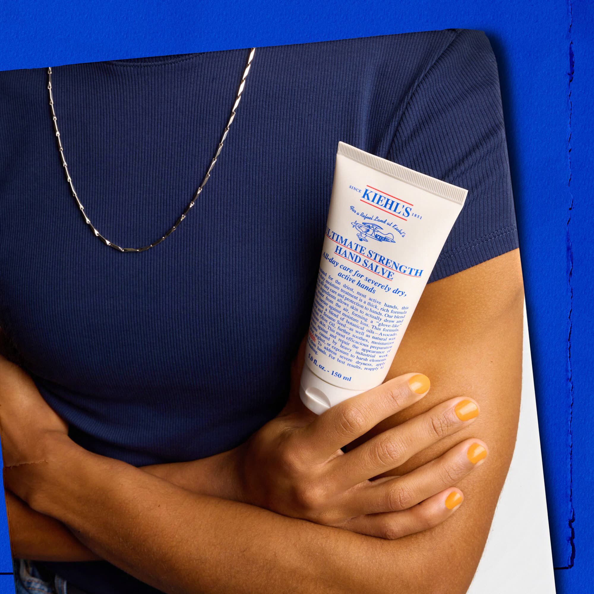 Model houdt een tube Kiehl's Ultimate Strength Hand Salve vast