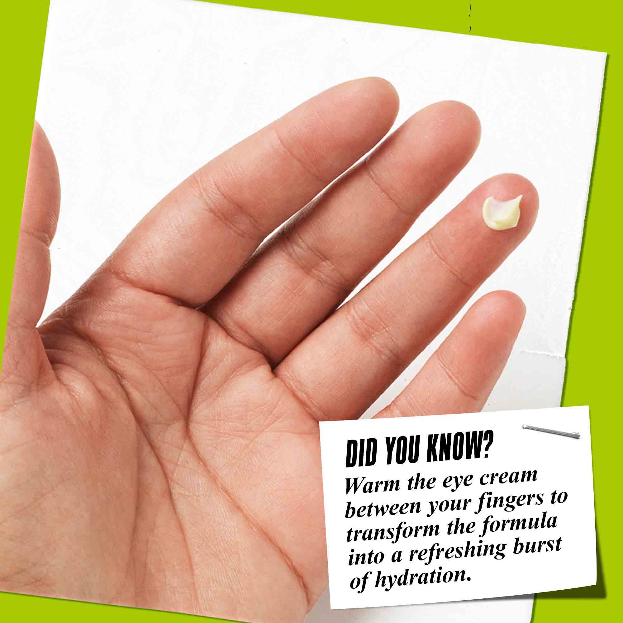A finger holding a dab of Creamy Avocado Eye Treatment with a tip about warming the formula for better application.