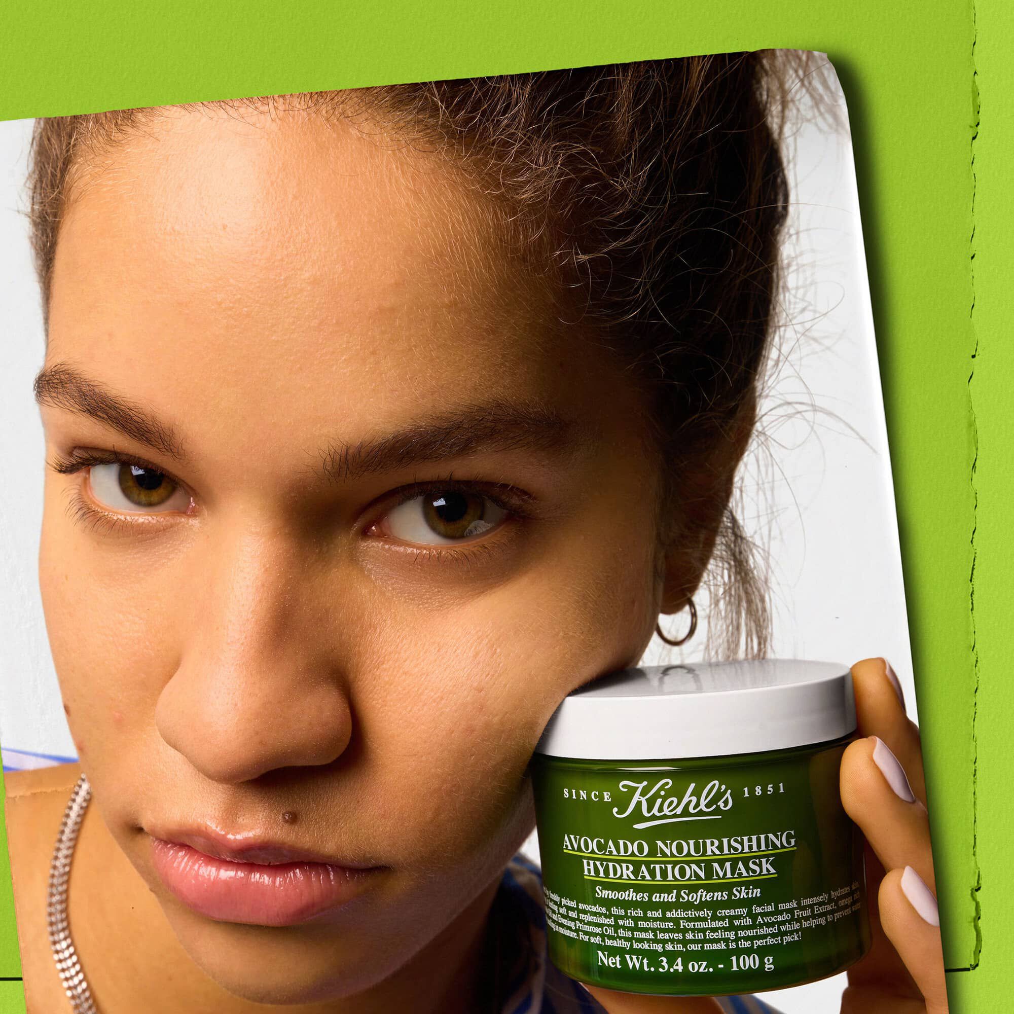 Model houdt een pot Kiehl's Avocado Nourishing Hydration Mask vast - maakt de huid glad en zacht