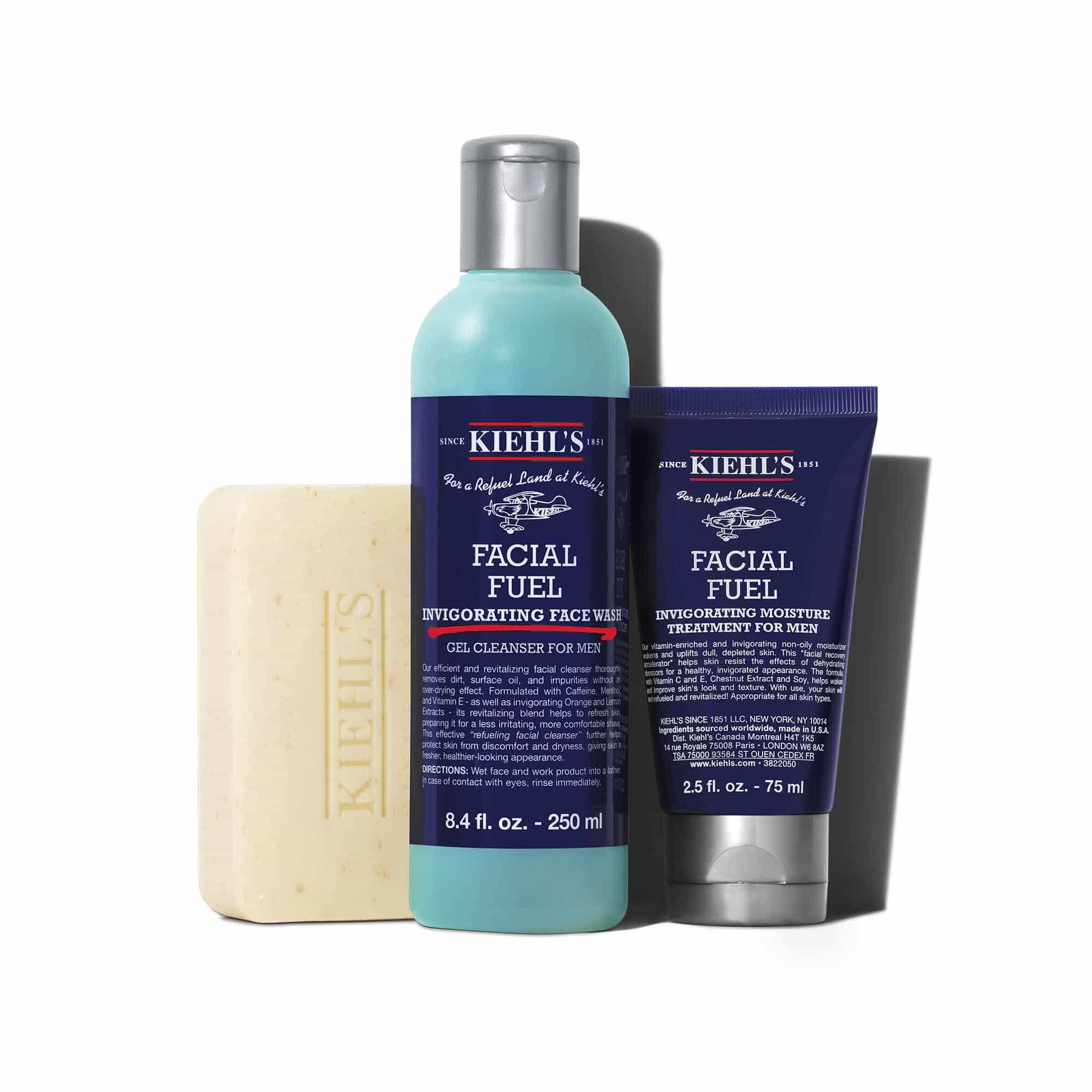 Een afbeelding met drie Kiehl's producten die een schaduw werpen tegen een witte achtergrond: een staaf "KIEHL'S 'ULTIMATE MAN' BODY SCRUB SOAP", een blauwe fles "KIEHL'S FACIAL FUEL ENERGIZING FACE WASH" en een donkerblauwe tube "KIEHL'S FACIAL FUEL MOISTURIZER".