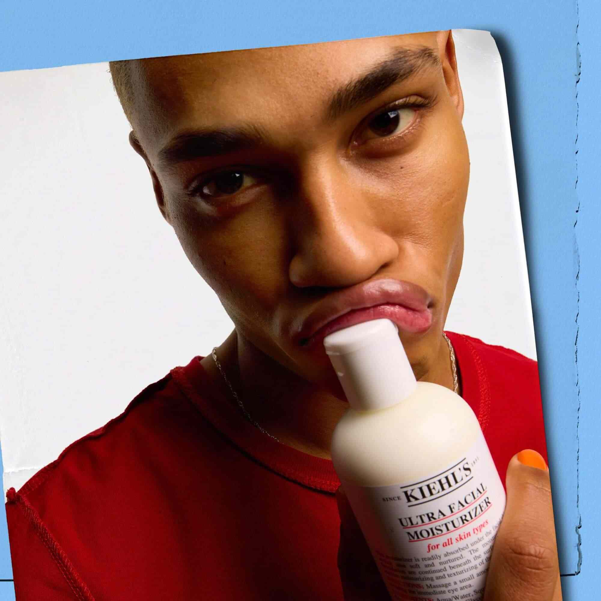 Model dat een fles Kiehl's Ultra Facial Moisturizer tegen de lippen drukt