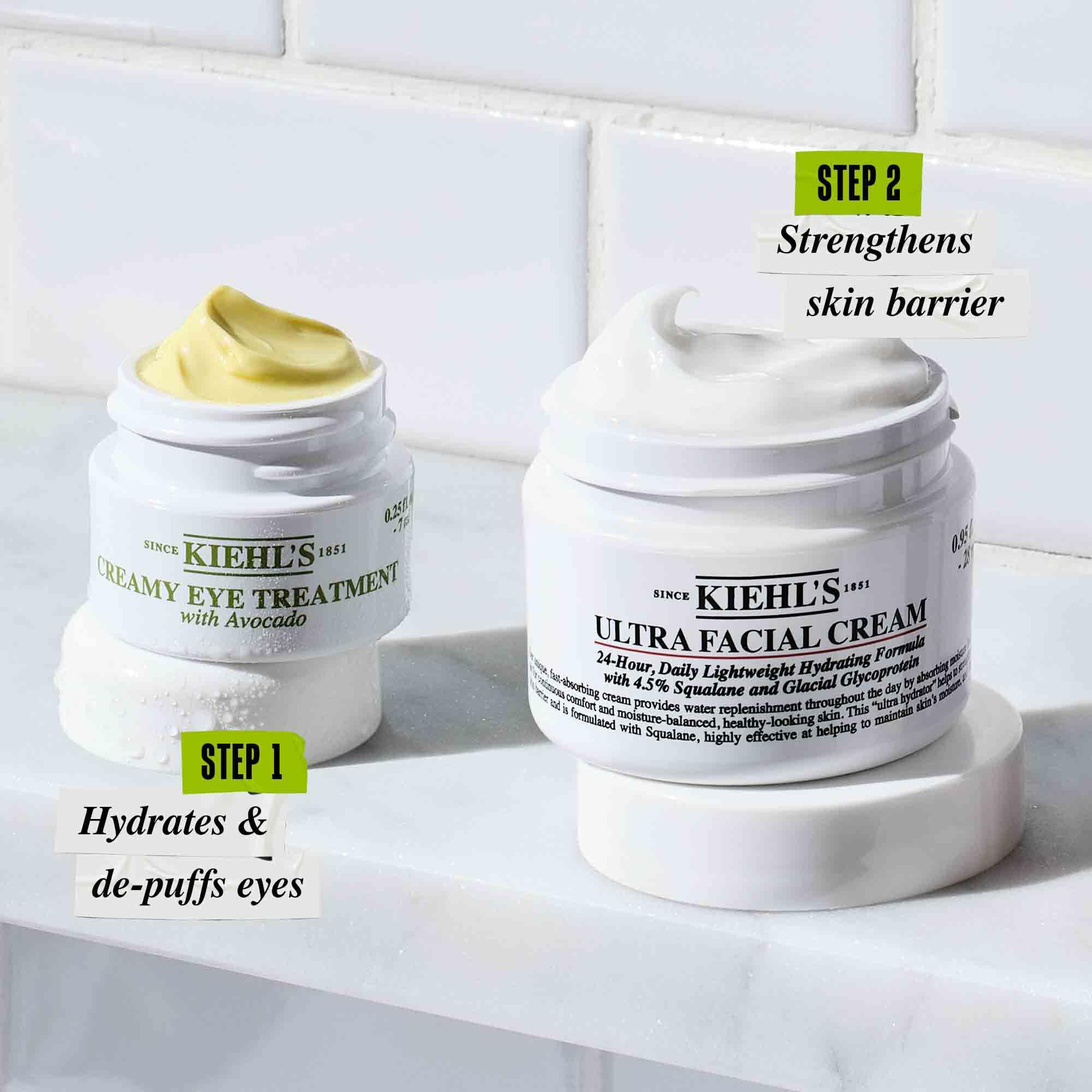 Kiehl’s Creamy Avocado Eye Treatment and Ultra Facial Cream jars labeled as Step 1 and Step 2 in a skincare routine, displayed on a bathroom counter.