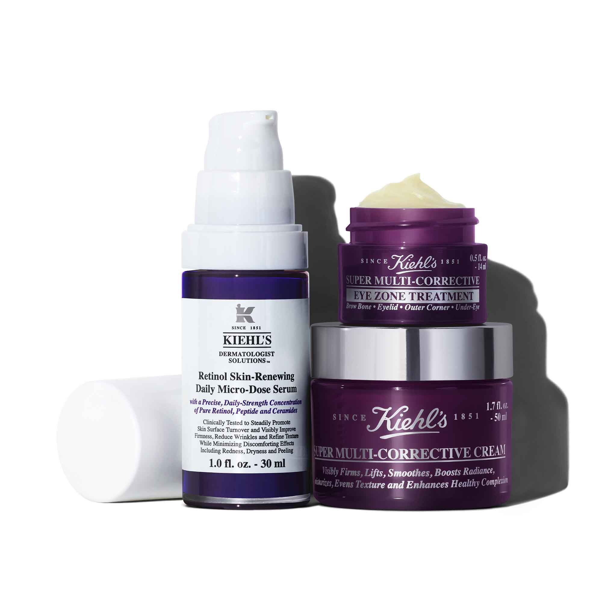 Een witte en paarse fles Retinol Skin-Renewing Daily Micro-Dose Serum, een kleine paarse pot Super Multi-Corrective Eye Zone Treatment en een grotere paarse pot Super Multi-Corrective Cream, en de hele set werpt een schaduw op een witte achtergrond.